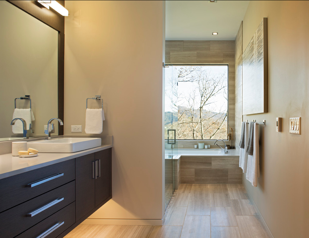 Cette image montre une grande salle de bain principale design en bois foncé avec un placard à porte plane, une baignoire encastrée, un carrelage gris, un carrelage beige, un carrelage de pierre, un sol en calcaire, une vasque, un plan de toilette en quartz modifié, une douche à l'italienne et un mur beige.