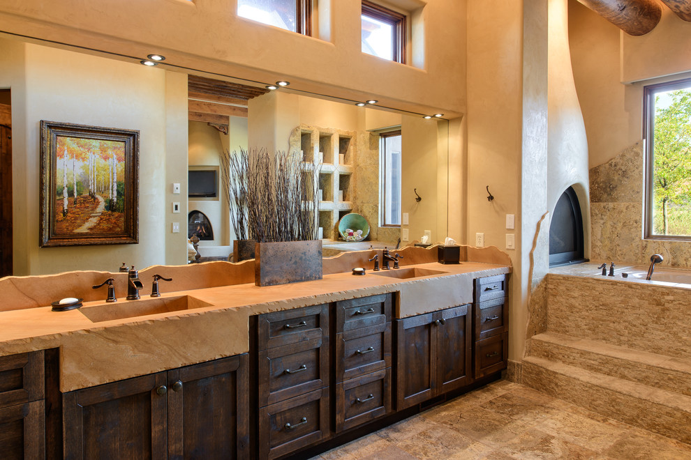 Cette image montre une salle de bain sud-ouest américain en bois foncé avec un lavabo intégré, un placard à porte shaker, un mur beige et un sol en ardoise.