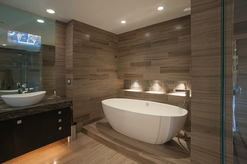Inspiration for a small contemporary ensuite bathroom in Cincinnati with a vessel sink, flat-panel cabinets, dark wood cabinets, granite worktops, a freestanding bath, a walk-in shower, beige tiles, porcelain tiles and porcelain flooring.