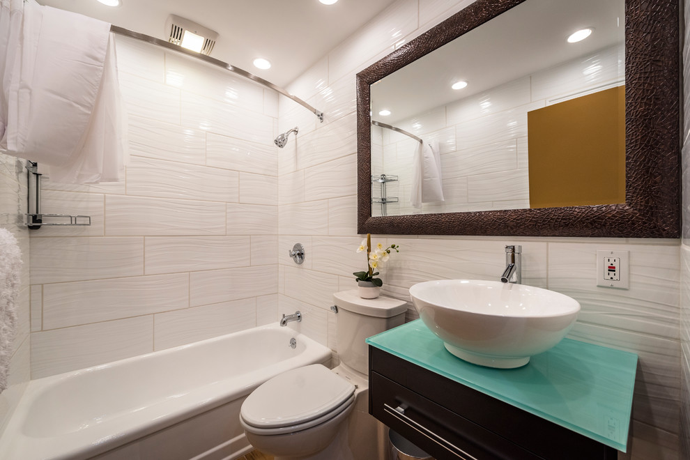 Свежая идея для дизайна: маленькая ванная комната в стиле неоклассика (современная классика) с плоскими фасадами, черными фасадами, ванной в нише, душем над ванной, раздельным унитазом, белой плиткой, керамогранитной плиткой, белыми стенами, полом из керамогранита, настольной раковиной, стеклянной столешницей и шторкой для ванной для на участке и в саду - отличное фото интерьера