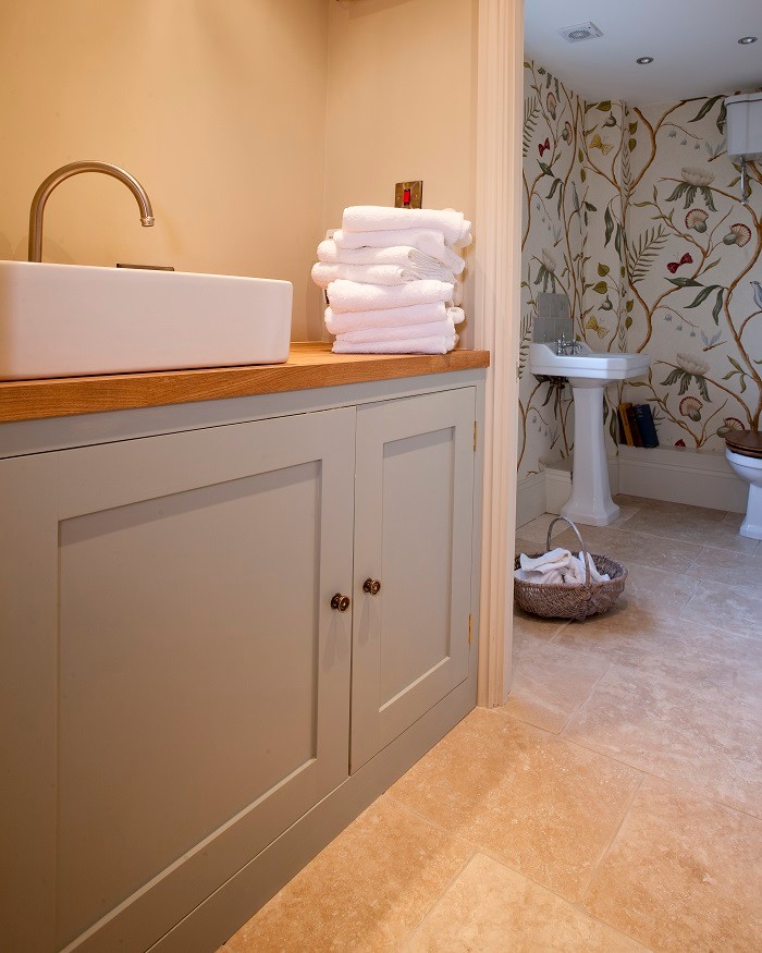 Inredning av ett lantligt badrum, med ett avlångt handfat, en öppen dusch, en toalettstol med hel cisternkåpa, beige väggar och klinkergolv i terrakotta