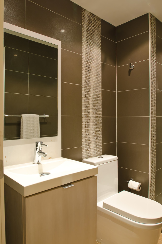 Design ideas for a small contemporary shower room bathroom in Other with flat-panel cabinets, light wood cabinets, solid surface worktops, brown tiles, ceramic tiles, an alcove shower, a one-piece toilet, an integrated sink, brown walls and ceramic flooring.