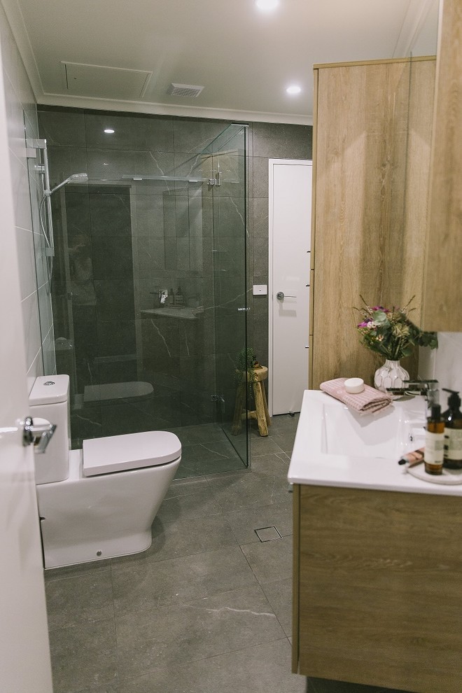 Ispirazione per una piccola stanza da bagno con doccia moderna con consolle stile comò, ante in legno chiaro, piastrelle in gres porcellanato, pavimento in gres porcellanato e pavimento grigio