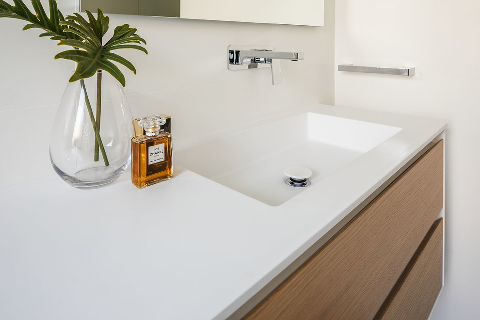 Design ideas for a medium sized contemporary ensuite bathroom in Perth with light wood cabinets, white tiles, white walls, ceramic flooring, an integrated sink, solid surface worktops, beige floors and a hinged door.