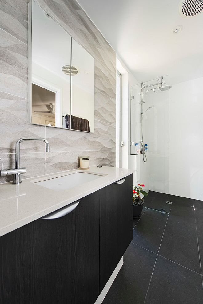 Exemple d'une salle de bain tendance en bois foncé de taille moyenne avec un lavabo posé, un placard à porte plane, une baignoire d'angle, une douche ouverte, un carrelage gris et un mur blanc.