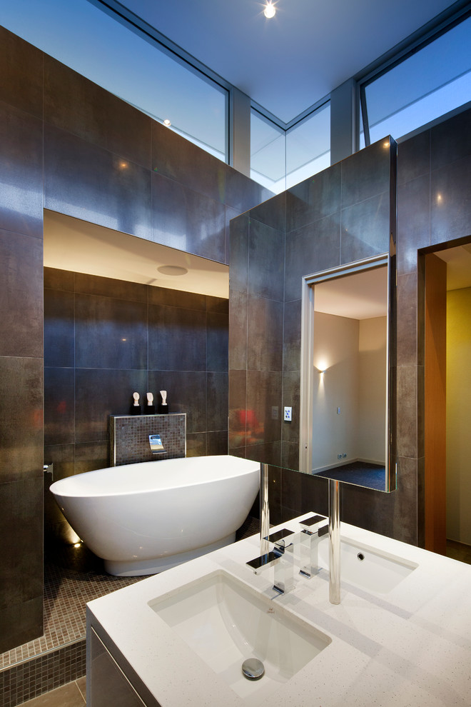 Пример оригинального дизайна: большая главная ванная комната в современном стиле с врезной раковиной, отдельно стоящей ванной, серой плиткой, металлической плиткой, коричневыми стенами, плоскими фасадами, белыми фасадами и столешницей из искусственного кварца