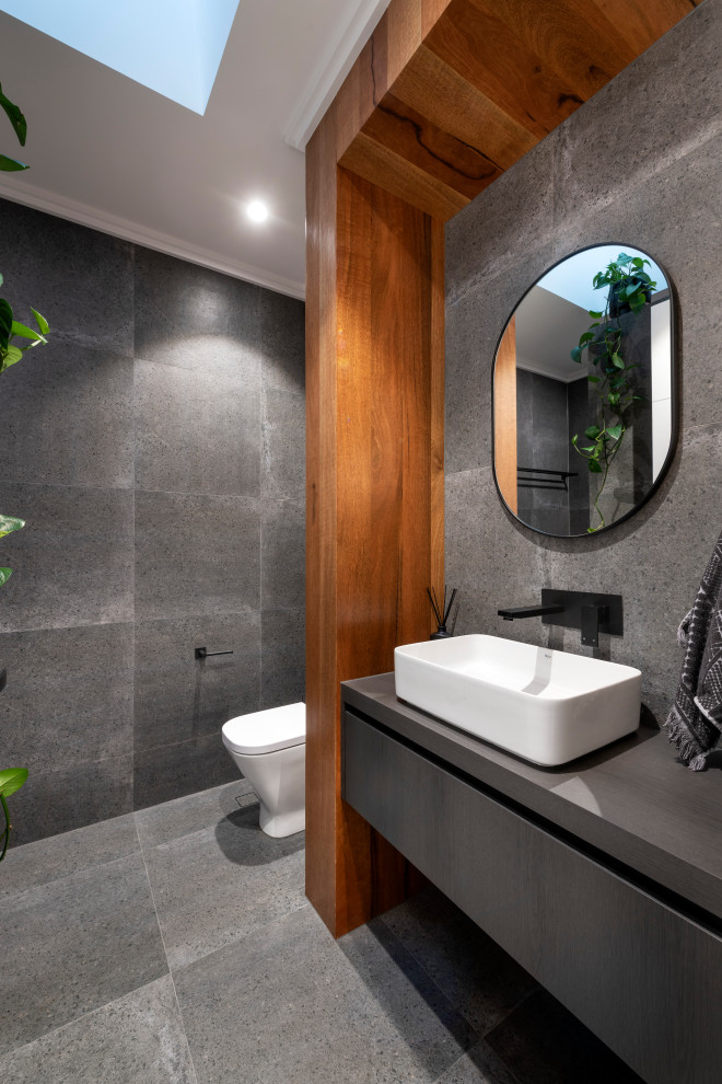 Idée de décoration pour une salle d'eau design de taille moyenne avec un placard à porte plane, des portes de placard grises, un carrelage gris, une vasque, un sol gris et un plan de toilette gris.