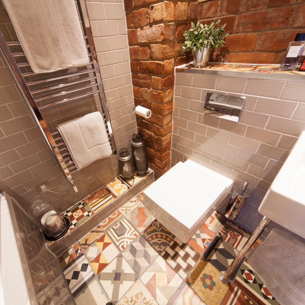 Bild på ett litet eklektiskt badrum för barn, med ett konsol handfat, ett platsbyggt badkar, en dusch/badkar-kombination, en vägghängd toalettstol, flerfärgad kakel, cementkakel, grå väggar och klinkergolv i keramik