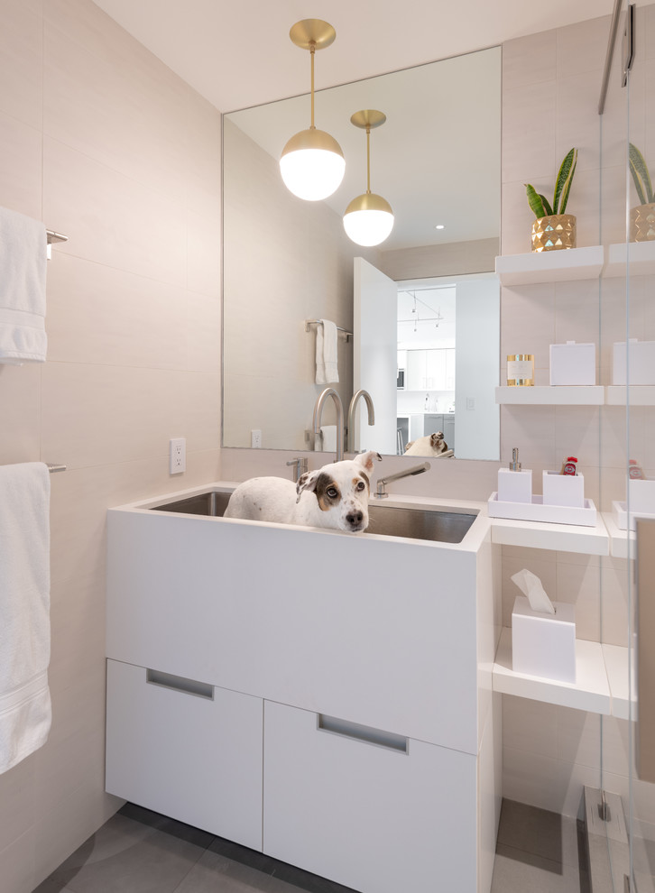 На фото: ванная комната в современном стиле с белыми фасадами, бежевой плиткой, бежевыми стенами, душевой кабиной, раковиной с несколькими смесителями, серым полом и белой столешницей