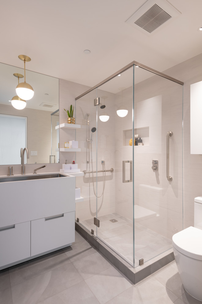 Пример оригинального дизайна: ванная комната в современном стиле с белыми фасадами, бежевой плиткой, бежевыми стенами, раковиной с несколькими смесителями и серым полом