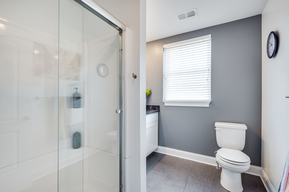 На фото: ванная комната среднего размера в современном стиле с фасадами в стиле шейкер, белыми фасадами, душем в нише, раздельным унитазом, серыми стенами, душевой кабиной, врезной раковиной, столешницей из гранита, серым полом и душем с раздвижными дверями с