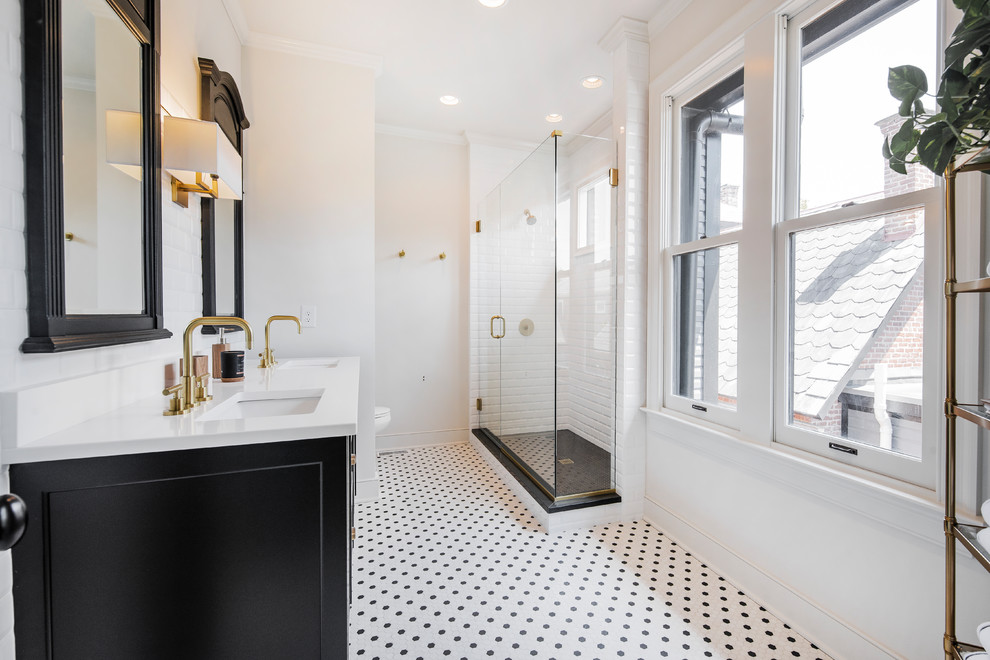 Bild på ett vintage vit vitt badrum, med luckor med infälld panel, svarta skåp, en hörndusch, en toalettstol med hel cisternkåpa, vit kakel, vita väggar, mosaikgolv, ett undermonterad handfat, vitt golv och dusch med gångjärnsdörr