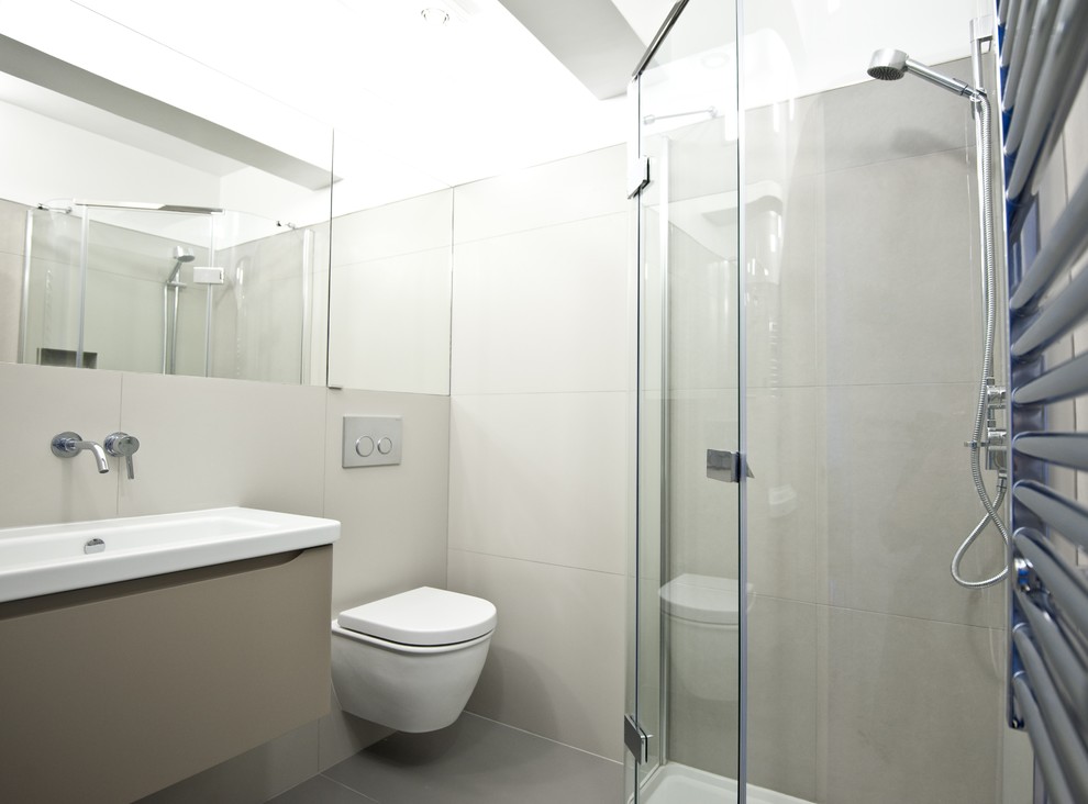 Small contemporary bathroom in London with a wall-mounted sink, a corner shower, a wall mounted toilet, grey tiles, porcelain tiles, grey walls and porcelain flooring.