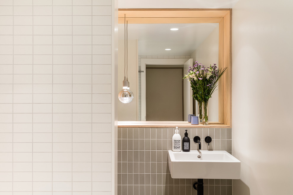 Small family bathroom in London with a built-in bath, a shower/bath combination, a wall mounted toilet, green tiles, white walls, porcelain flooring, a wall-mounted sink, green floors and a hinged door.