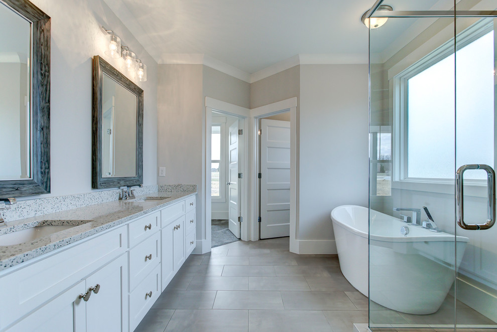 Стильный дизайн: большая главная ванная комната в стиле кантри с фасадами в стиле шейкер, белыми фасадами, отдельно стоящей ванной, угловым душем, унитазом-моноблоком, серой плиткой, керамической плиткой, серыми стенами, полом из керамогранита, врезной раковиной, столешницей из искусственного кварца, серым полом, душем с распашными дверями и белой столешницей - последний тренд