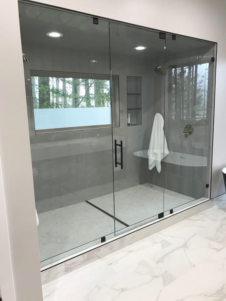 Large contemporary ensuite bathroom in Portland with shaker cabinets, black cabinets, a freestanding bath, a double shower, a one-piece toilet, grey tiles, porcelain tiles, grey walls, porcelain flooring, a trough sink, engineered stone worktops, multi-coloured floors, a hinged door and white worktops.
