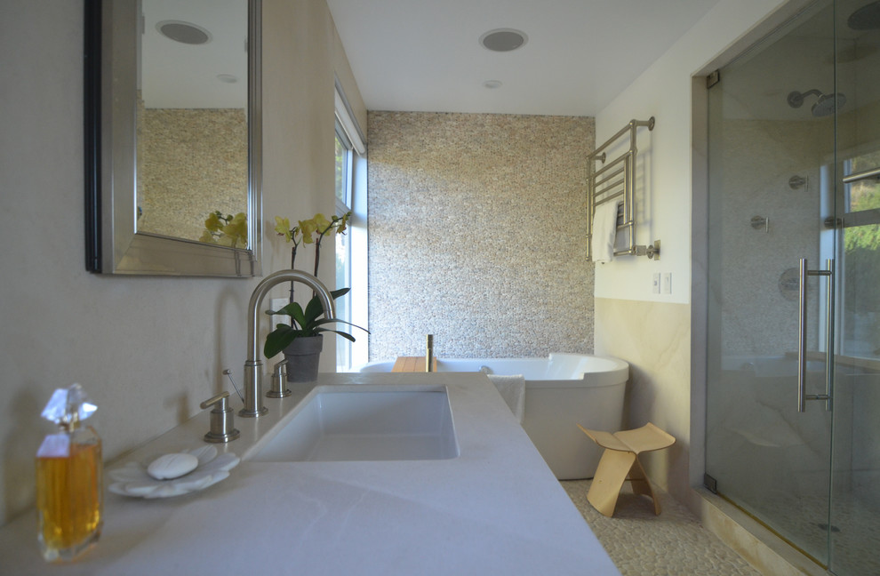Источник вдохновения для домашнего уюта: ванная комната среднего размера в средиземноморском стиле с плоскими фасадами, светлыми деревянными фасадами, отдельно стоящей ванной, открытым душем, раздельным унитазом, бежевой плиткой, плиткой из известняка, белыми стенами, полом из галечной плитки, врезной раковиной, столешницей из известняка, бежевым полом и душем с распашными дверями