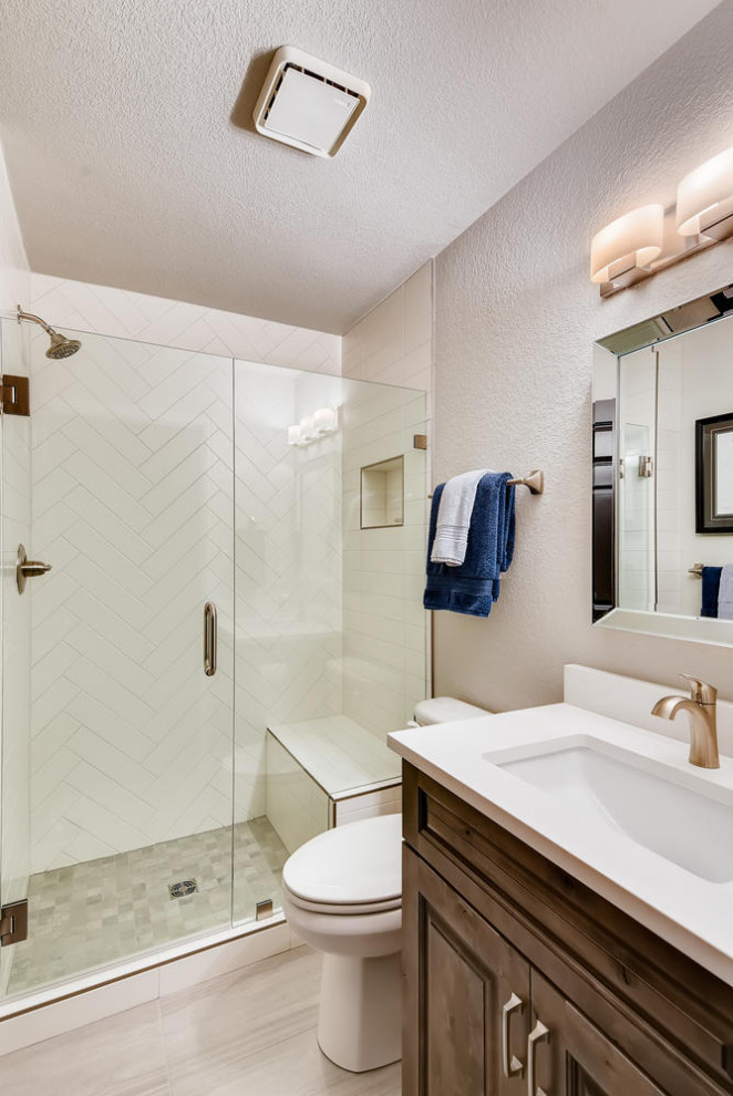 Example of a mid-sized classic 3/4 white tile and subway tile porcelain tile, gray floor and single-sink bathroom design in Denver with raised-panel cabinets, medium tone wood cabinets, a two-piece toilet, gray walls, an undermount sink, quartz countertops, a hinged shower door, white countertops and a built-in vanity