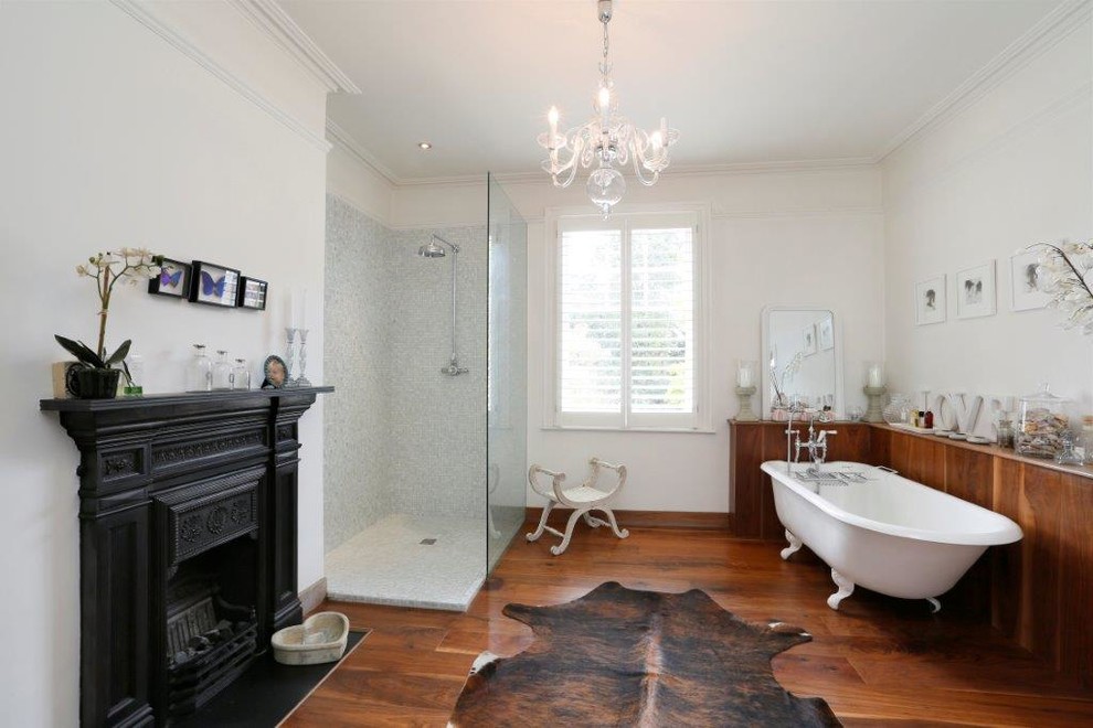 Modelo de cuarto de baño tradicional renovado con bañera con patas, ducha abierta, paredes blancas, suelo de madera en tonos medios y ducha abierta