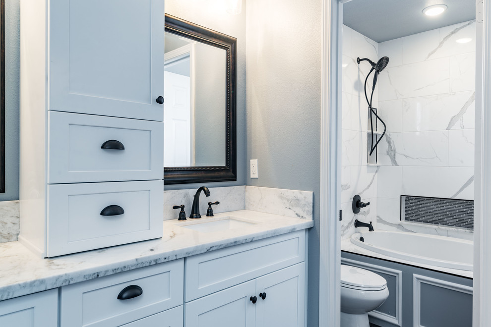 Inredning av ett klassiskt mellanstort en-suite badrum, med skåp i shakerstil, vita skåp, ett badkar i en alkov, en dusch/badkar-kombination, en toalettstol med separat cisternkåpa, vit kakel, marmorkakel, grå väggar, mörkt trägolv, ett undermonterad handfat, marmorbänkskiva, brunt golv och dusch med duschdraperi