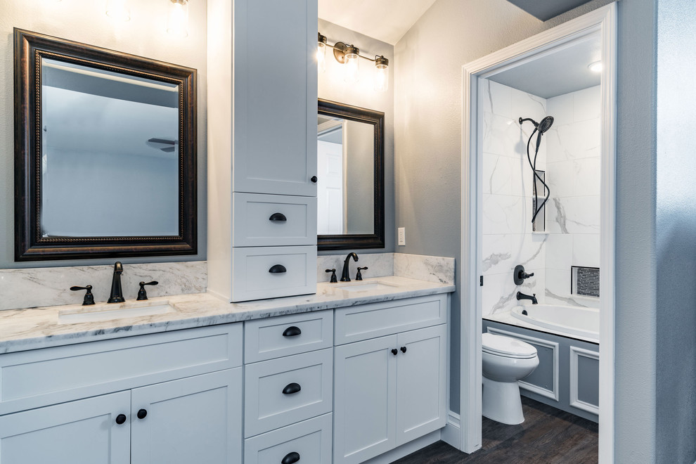 Example of a mid-sized transitional master white tile and marble tile dark wood floor and brown floor bathroom design in Other with shaker cabinets, white cabinets, a two-piece toilet, gray walls, an undermount sink and marble countertops