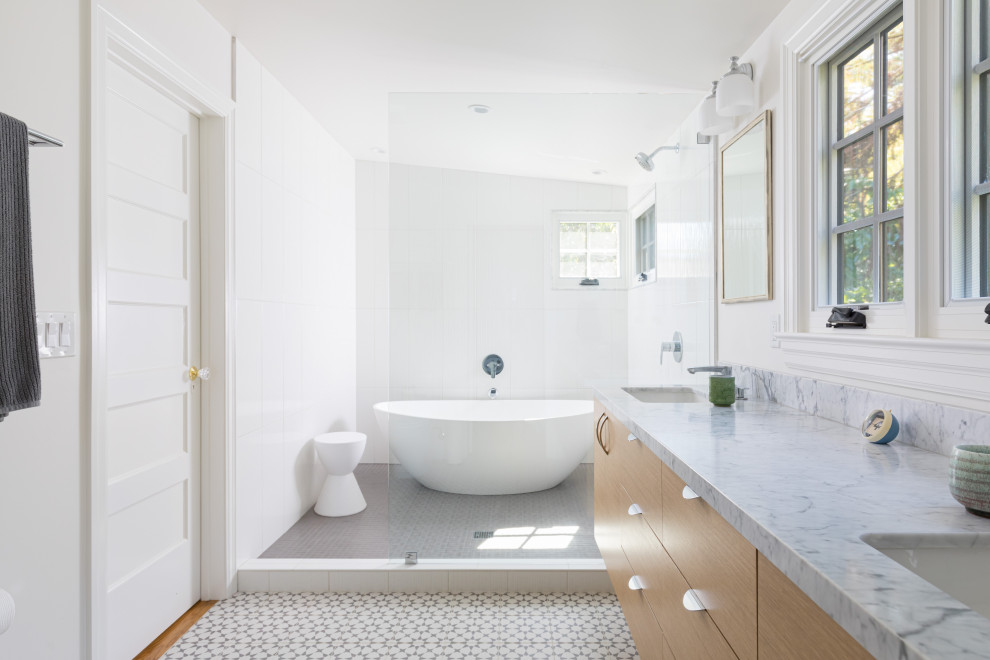 Photo of a classic ensuite wet room bathroom in San Francisco with flat-panel cabinets, medium wood cabinets, a freestanding bath, white tiles, white walls, a submerged sink, multi-coloured floors, an open shower and grey worktops.