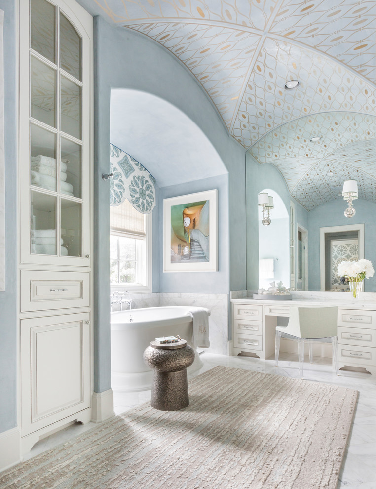 Aménagement d'une salle de bain principale classique avec des portes de placard blanches, une baignoire indépendante, un mur bleu et un placard avec porte à panneau encastré.