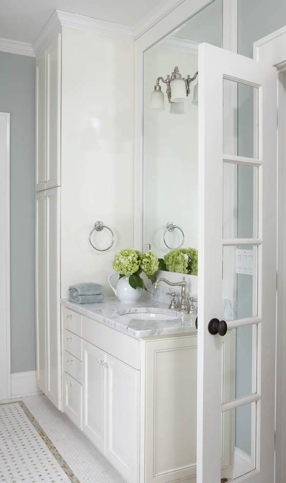 Modelo de cuarto de baño clásico con lavabo bajoencimera, armarios con paneles empotrados, puertas de armario grises y encimera de acrílico