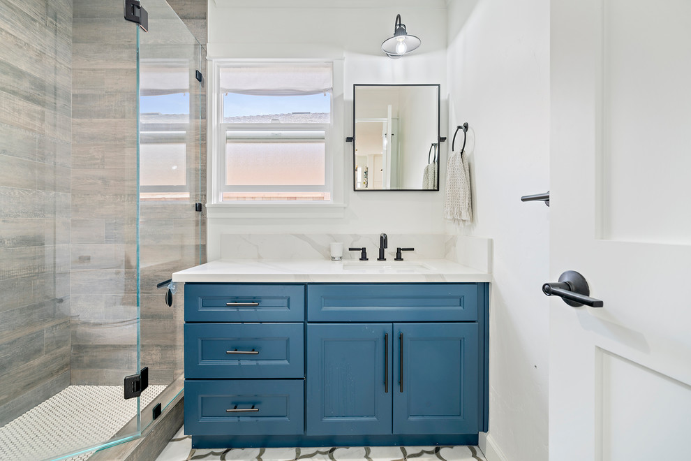 Design ideas for a farmhouse bathroom in San Francisco with recessed-panel cabinets, blue cabinets, an alcove shower, beige tiles, white walls, a submerged sink, multi-coloured floors, a hinged door and white worktops.