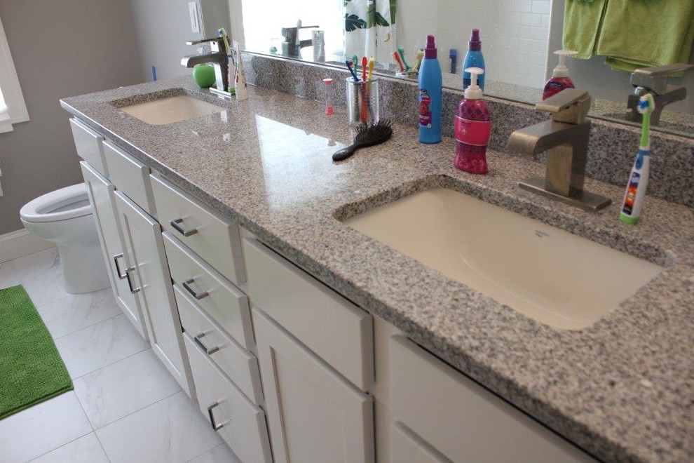 This is an example of a medium sized contemporary bathroom in Detroit with a submerged sink, flat-panel cabinets, white cabinets, granite worktops, a two-piece toilet, white tiles, porcelain tiles, grey walls and porcelain flooring.