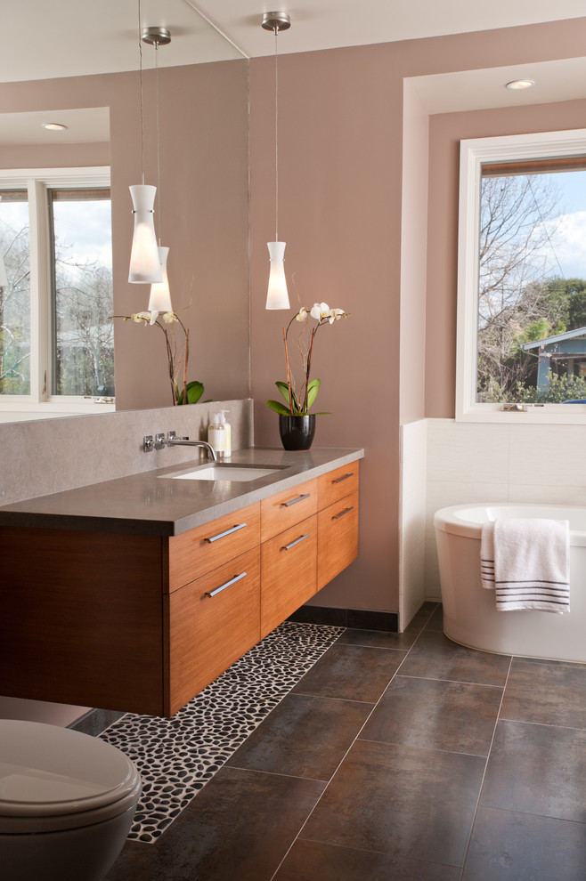 Foto de cuarto de baño contemporáneo con armarios con paneles lisos, puertas de armario de madera oscura, bañera exenta y encimeras grises