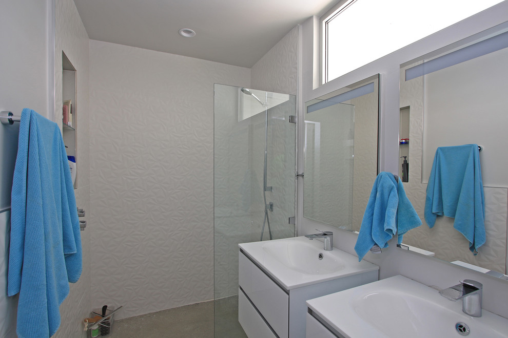 Imagen de cuarto de baño principal retro de tamaño medio con armarios con paneles lisos, puertas de armario blancas, ducha empotrada, paredes blancas, suelo de cemento, lavabo integrado, suelo gris y ducha abierta