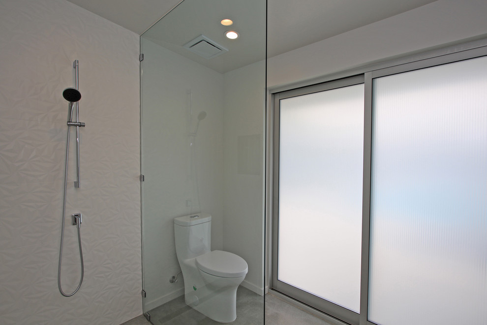 Immagine di una stanza da bagno con doccia minimalista di medie dimensioni con doccia aperta, doccia aperta, WC monopezzo, pareti bianche, pavimento in cemento e pavimento grigio