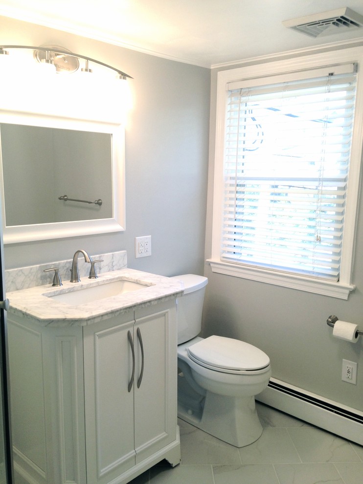 Klassisk inredning av ett litet badrum med dusch, med ett integrerad handfat, marmorbänkskiva, en hörndusch, en toalettstol med separat cisternkåpa, vit kakel, porslinskakel, grå väggar och klinkergolv i porslin