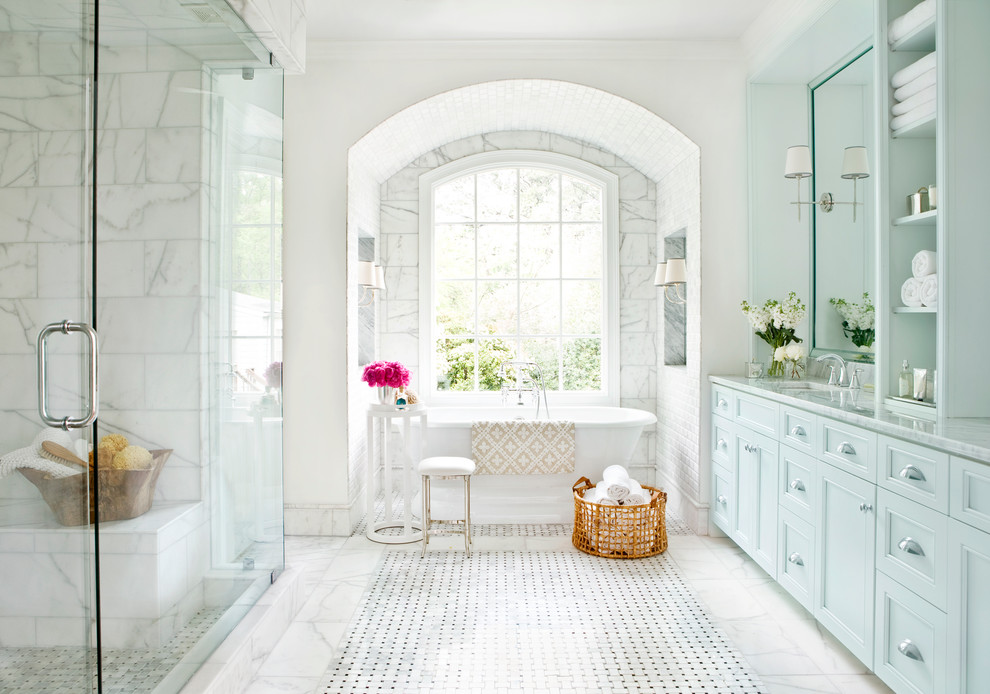 Aménagement d'une grande douche en alcôve principale classique avec une baignoire indépendante, des portes de placard bleues, un placard avec porte à panneau encastré, un carrelage gris, un carrelage blanc, un mur blanc, un sol en marbre, un lavabo encastré, un plan de toilette en marbre et du carrelage en marbre.