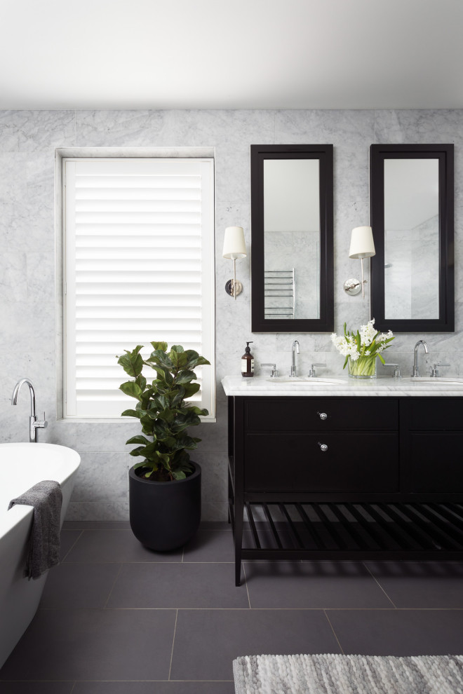 Пример оригинального дизайна: детская ванная комната среднего размера в стиле неоклассика (современная классика) с фасадами в стиле шейкер, черными фасадами, отдельно стоящей ванной, двойным душем, унитазом-моноблоком, серой плиткой, мраморной плиткой, серыми стенами, полом из керамической плитки, врезной раковиной, мраморной столешницей, серым полом, открытым душем и серой столешницей