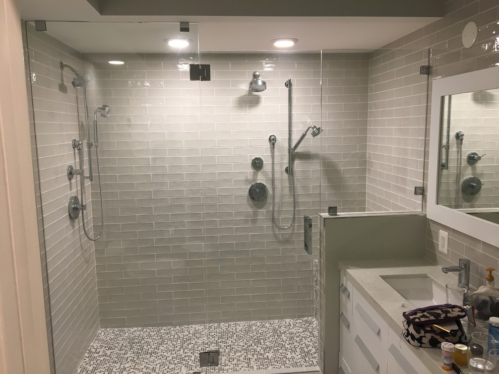 Идея дизайна: главная ванная комната среднего размера в современном стиле с плоскими фасадами, белыми фасадами, двойным душем, унитазом-моноблоком, серой плиткой, стеклянной плиткой, серыми стенами, полом из керамической плитки, врезной раковиной, столешницей из гранита, серым полом и душем с распашными дверями