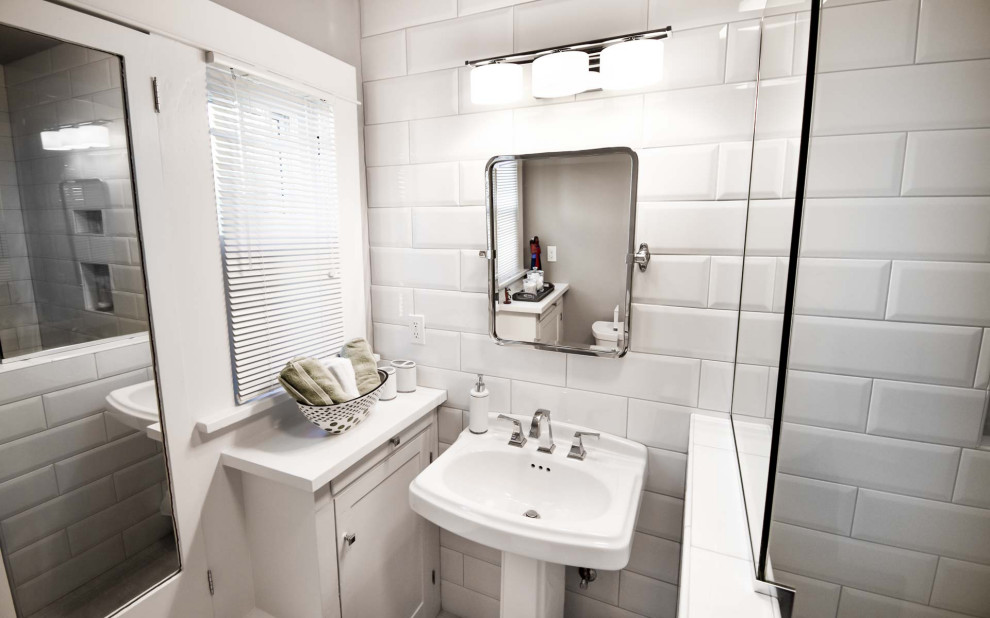 На фото: маленькая главная ванная комната в стиле неоклассика (современная классика) с ванной в нише, душем над ванной, раздельным унитазом, белой плиткой, плиткой кабанчик, белыми стенами, полом из керамической плитки, раковиной с пьедесталом, столешницей из дерева, серым полом, душем с раздвижными дверями, белой столешницей, нишей и тумбой под одну раковину для на участке и в саду с