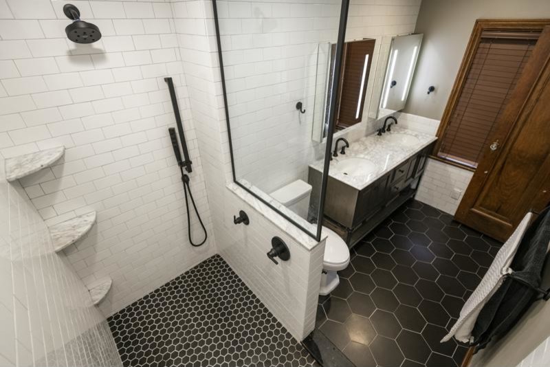 Inredning av ett industriellt mellanstort grå grått en-suite badrum, med luckor med infälld panel, skåp i mörkt trä, en öppen dusch, vit kakel, tunnelbanekakel, grå väggar, klinkergolv i keramik, ett undermonterad handfat, marmorbänkskiva, svart golv och med dusch som är öppen