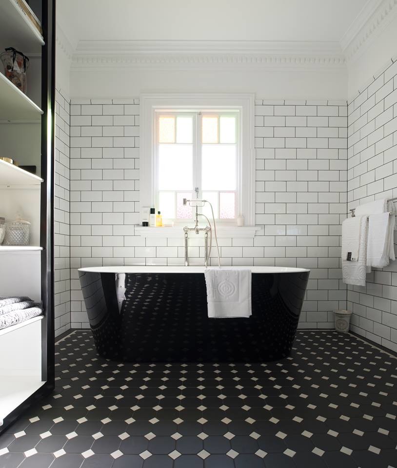 Exemple d'une grande salle de bain principale victorienne avec une baignoire indépendante, un sol en carrelage de porcelaine, un placard sans porte, un mur blanc, des portes de placard noires, un carrelage blanc, un carrelage métro, un plan de toilette en surface solide et un sol noir.