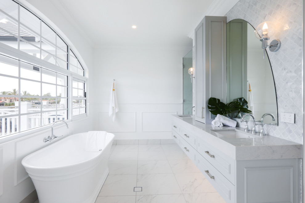 Nautical bathroom in Gold Coast - Tweed with raised-panel cabinets, grey cabinets, a freestanding bath, grey tiles, white walls, a submerged sink, white floors, grey worktops and double sinks.