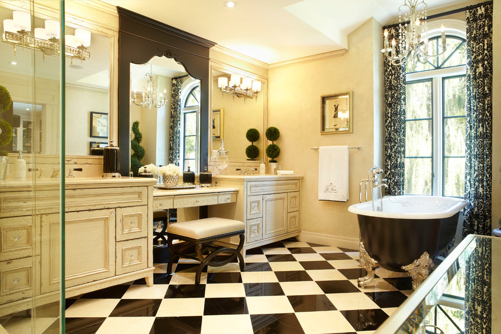 Пример оригинального дизайна: большая главная ванная комната: освещение в классическом стиле с ванной на ножках, искусственно-состаренными фасадами, черно-белой плиткой, бежевыми стенами, врезной раковиной и фасадами с утопленной филенкой