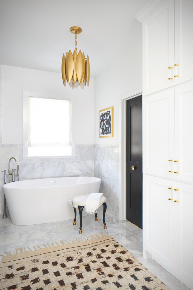 オースティンにあるトランジショナルスタイルのおしゃれなマスターバスルーム (落し込みパネル扉のキャビネット、白いキャビネット、置き型浴槽、マルチカラーの壁、グレーの床) の写真