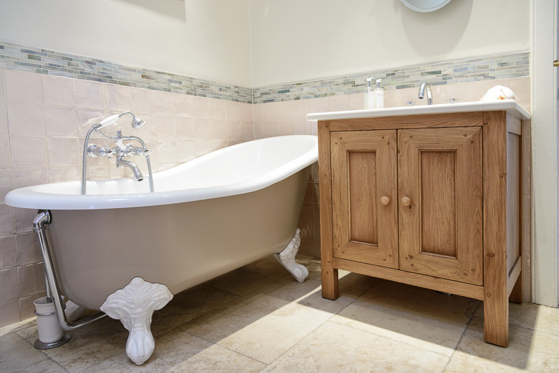 Exemple d'une petite salle de bain nature en bois brun avec un placard en trompe-l'oeil, une baignoire sur pieds, des carreaux de céramique, un mur beige, un sol en carrelage de porcelaine, un plan de toilette en calcaire et un carrelage beige.