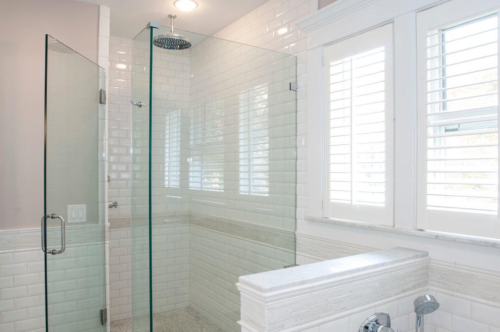 Inspiration for a mid-sized timeless 3/4 white tile and subway tile marble floor corner shower remodel in New York with beige walls, a drop-in sink, raised-panel cabinets, white cabinets, marble countertops, a wall-mount toilet and an undermount tub