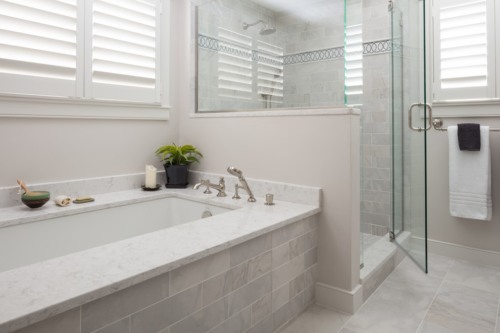На фото: большая главная ванная комната в классическом стиле с полновстраиваемой ванной, угловым душем, серой плиткой, серыми стенами, душем с распашными дверями, мраморной плиткой, мраморным полом, столешницей из искусственного кварца и серым полом