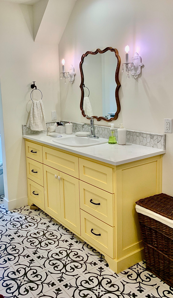 Example of a mid-sized country porcelain tile and multicolored floor bathroom design in Portland with shaker cabinets, yellow cabinets, white walls, a drop-in sink, quartz countertops and white countertops