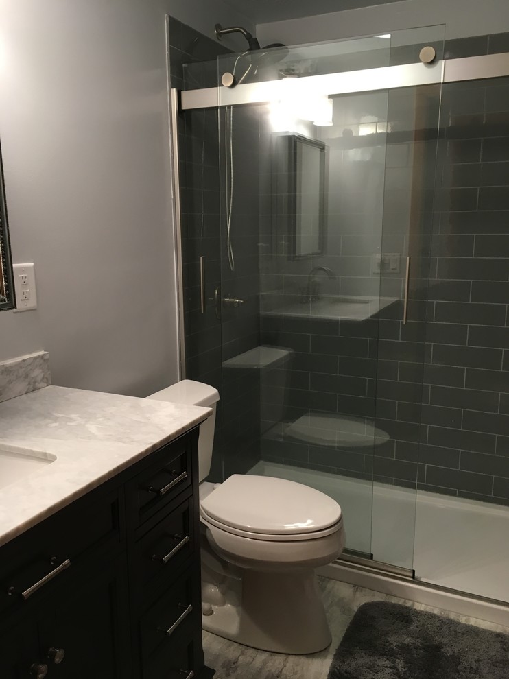 This is an example of a small modern ensuite bathroom in Other with raised-panel cabinets, grey cabinets, a built-in shower, a one-piece toilet, grey tiles, grey walls, vinyl flooring, a submerged sink, marble worktops, grey floors, a sliding door and white worktops.