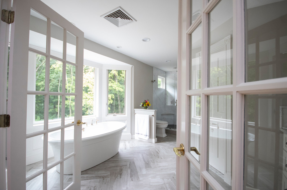 Immagine di una grande stanza da bagno padronale classica con ante con riquadro incassato, ante bianche, vasca freestanding, doccia a filo pavimento, WC a due pezzi, piastrelle bianche, piastrelle di marmo, pareti grigie, pavimento con piastrelle in ceramica, lavabo sottopiano, top in quarzite, pavimento grigio, porta doccia a battente e top grigio