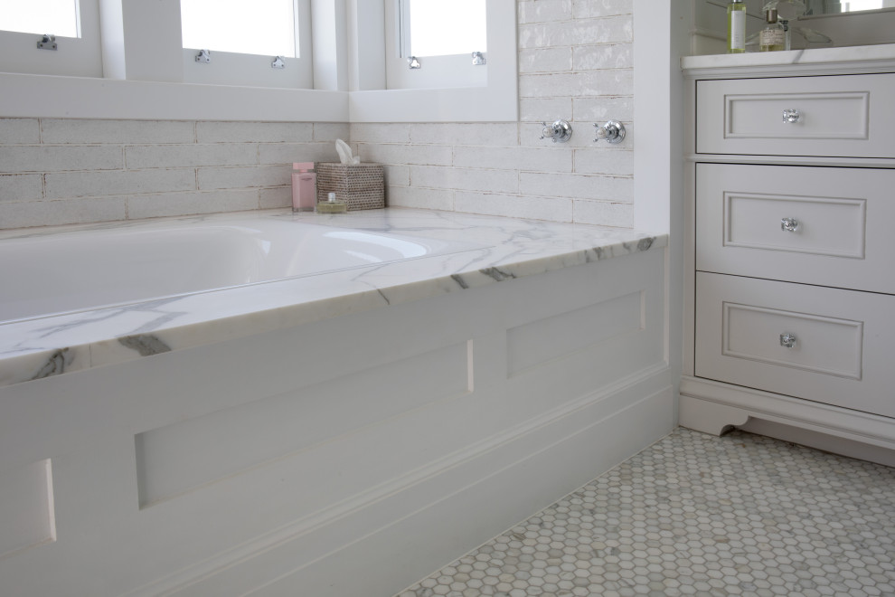 На фото: детская ванная комната в классическом стиле с фасадами в стиле шейкер, белыми фасадами, полновстраиваемой ванной, полом из мозаичной плитки, мраморной столешницей и встроенной тумбой с